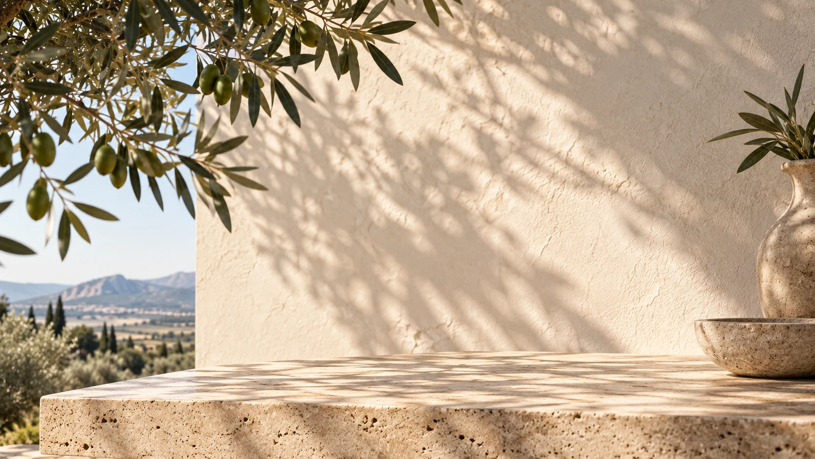 A travertine ledge below a sunlit plaster wall, olive branches overhead and the Akhisar valley beyond